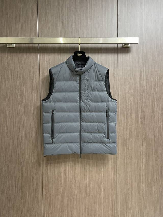 Moncler 立领羽绒背心马甲，采用轻盈尼龙面料制成，马甲呈现流畅简约设计，演绎贯穿男士系列的标志性精巧细节。这款基础保暖单品配有立领、拉链口袋和精巧标识饰边